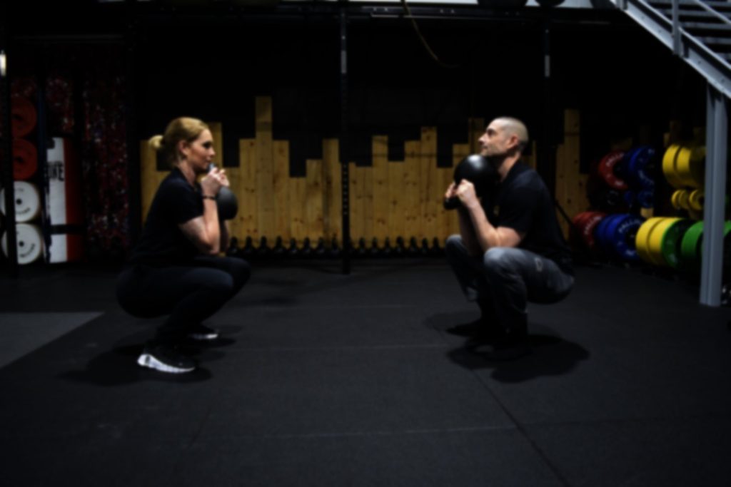 Deux coachs en squat avec kettlebell dans la salle Steel Training à Marines